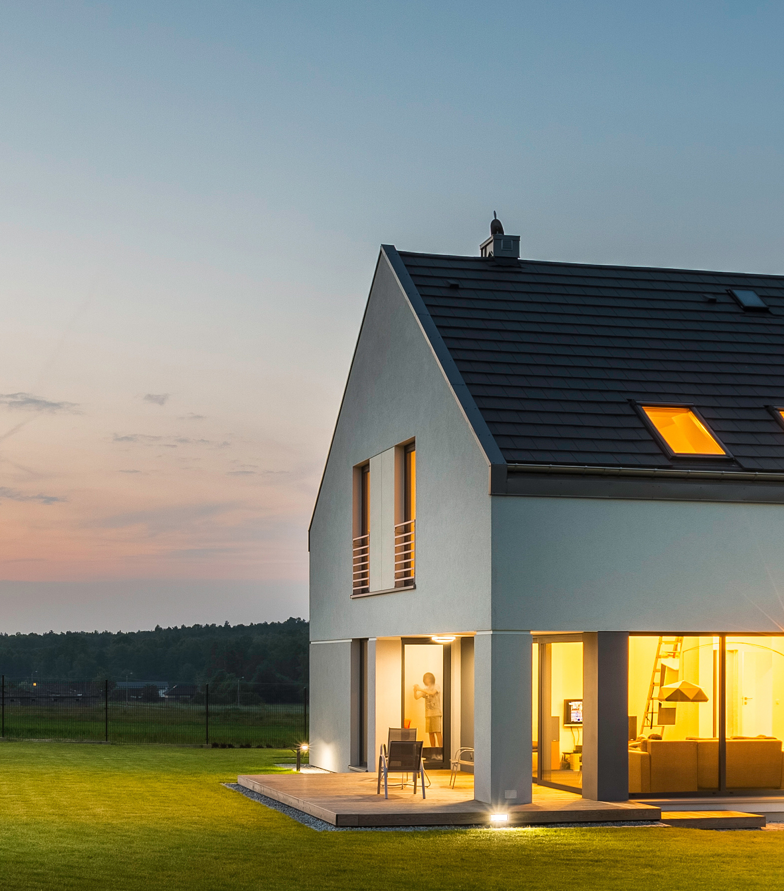 Panoramic photo of modern house with outdoor and indoor lighting, at night